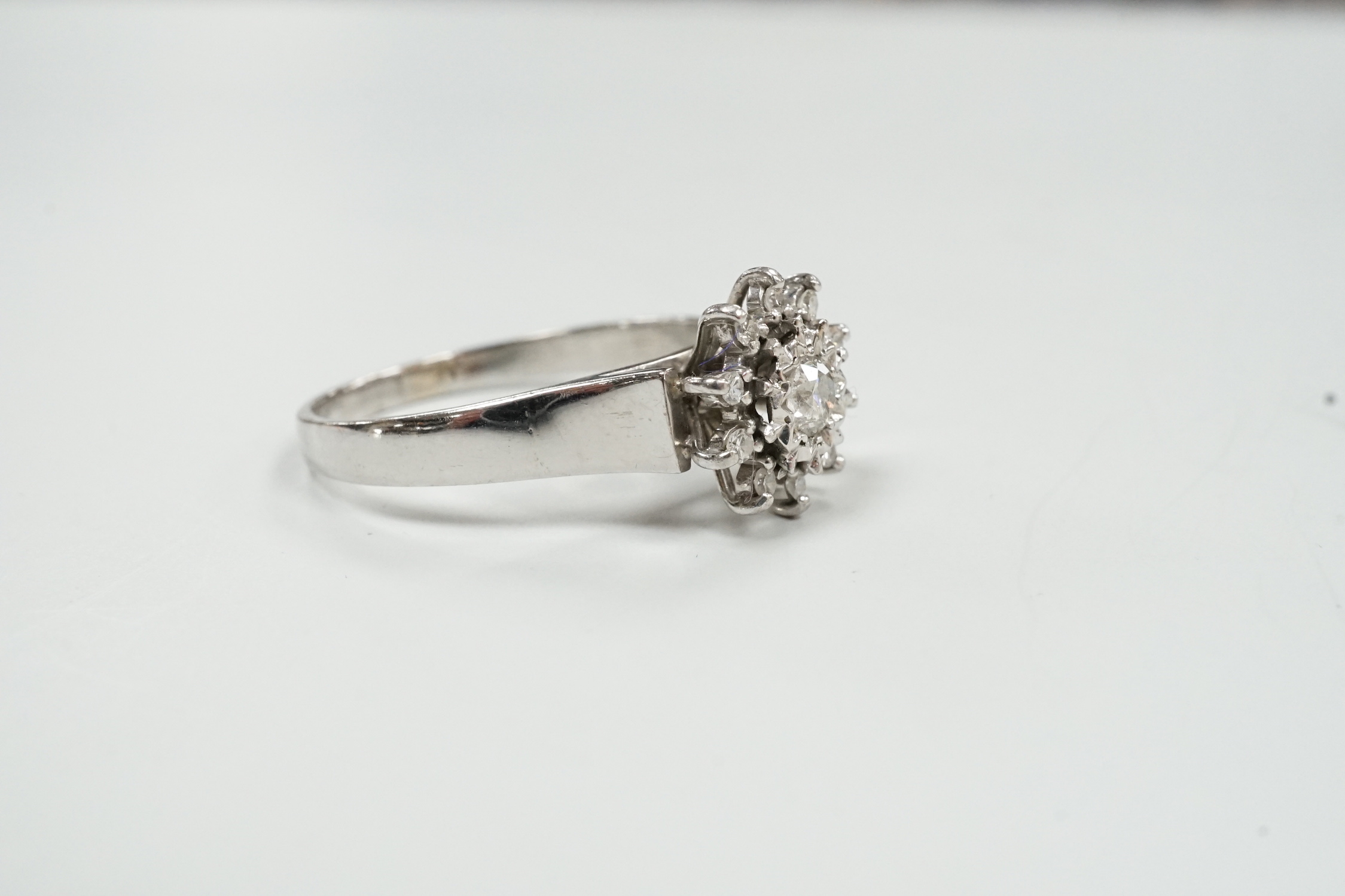 A modern 18ct white metal and diamond cluster set flower head ring, size U, gross weight 5 grams.